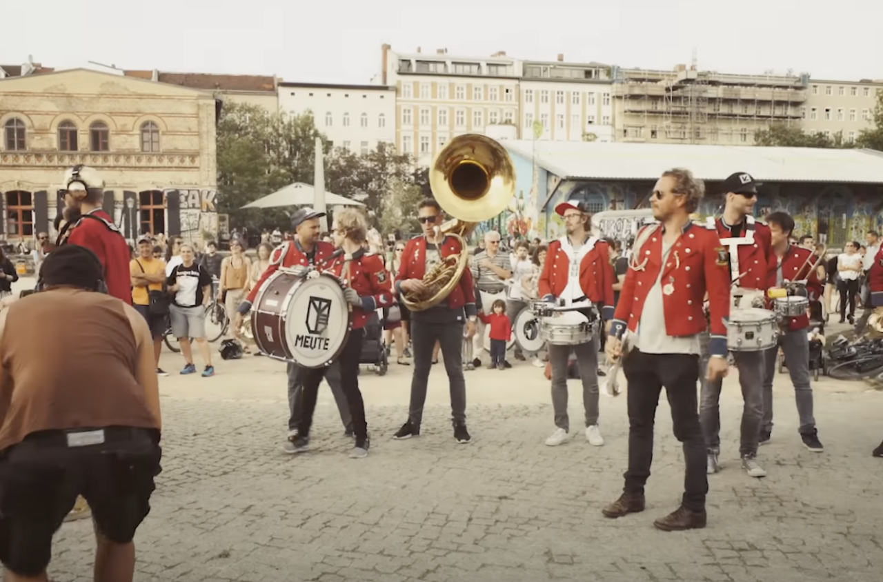 Marching band standing outdoors in red uniforms.