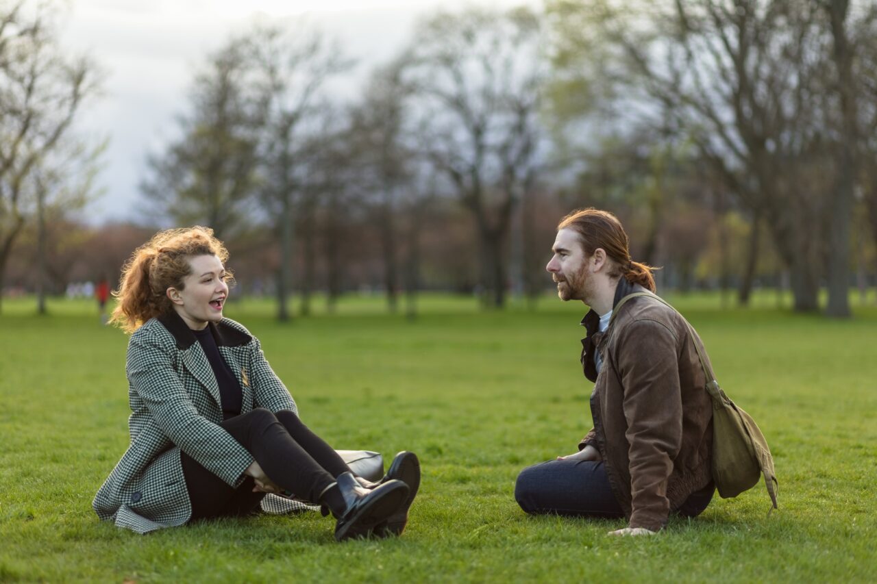 Two people sitting on the grass in a park