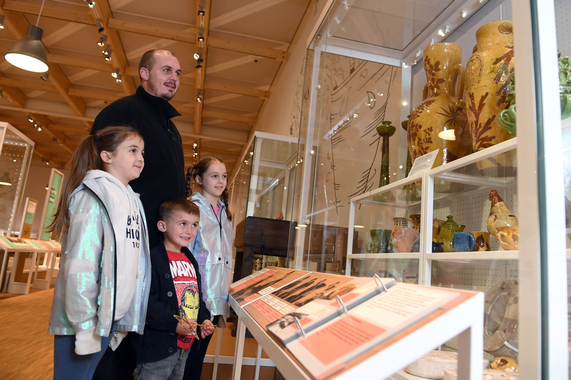 An adult and three children looking at a glass display.