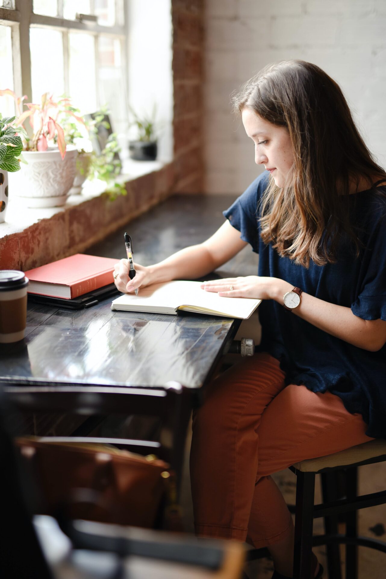 A person sitting in a cafe and writing in a book