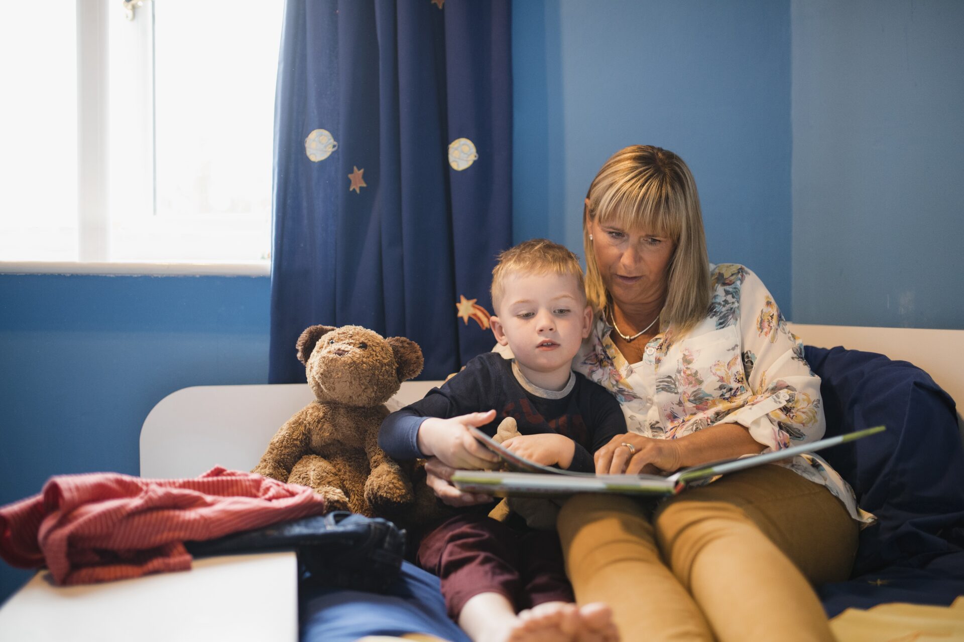 Grandmother and her grandson sitting in bed and reading a story before bedtime.