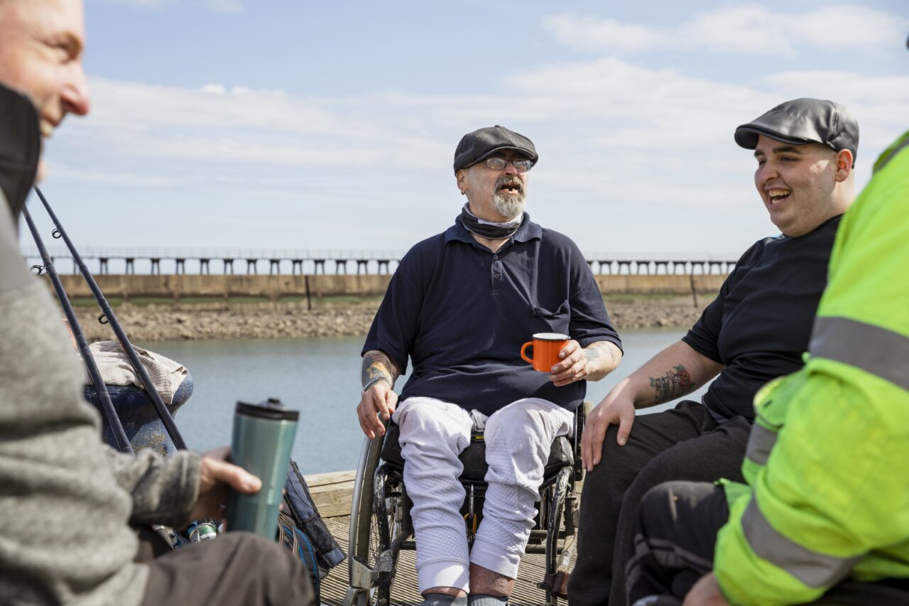 A group of people talking to eachother as they sit outside next to the sea