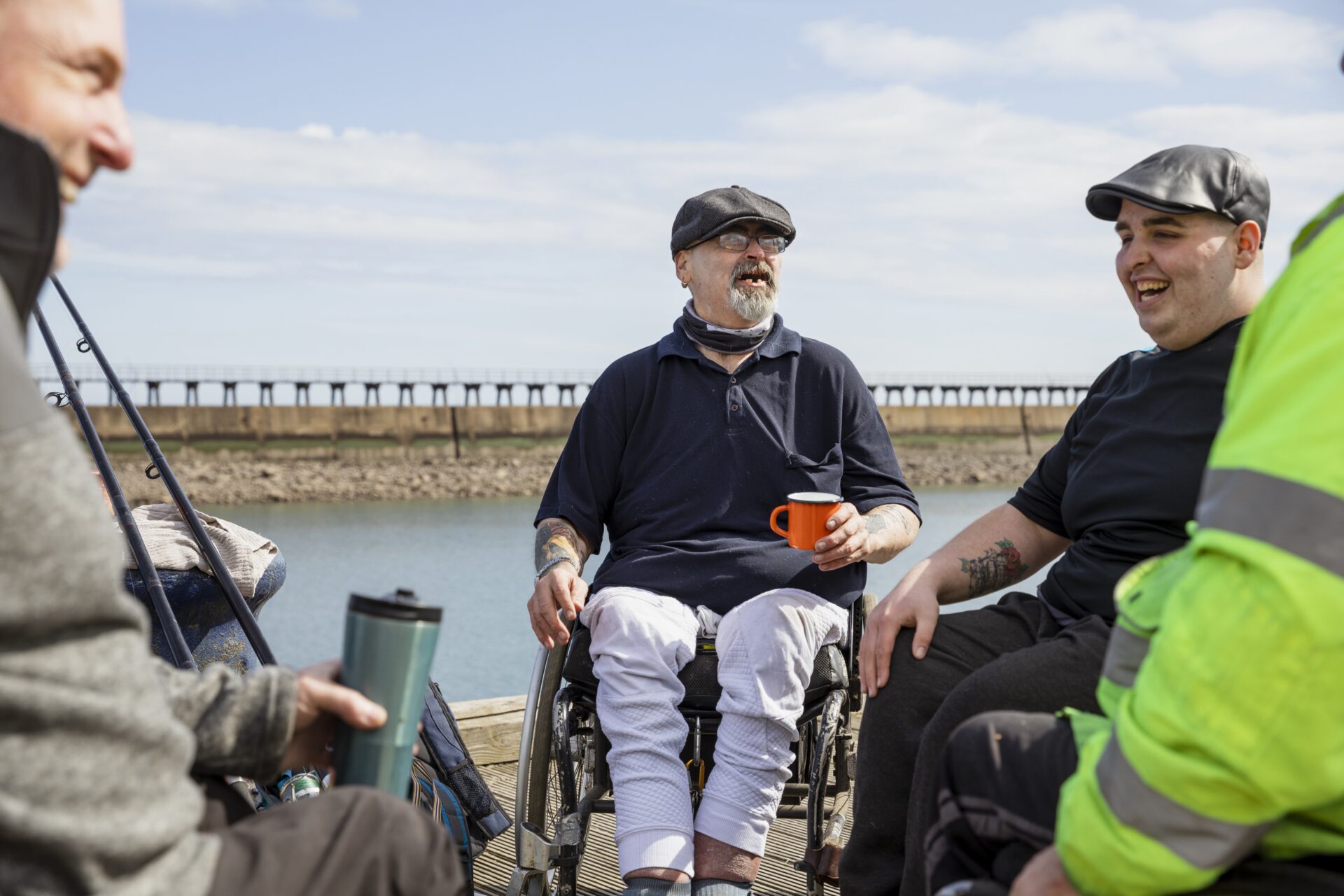 A group of people talking to eachother as they sit outside next to the sea
