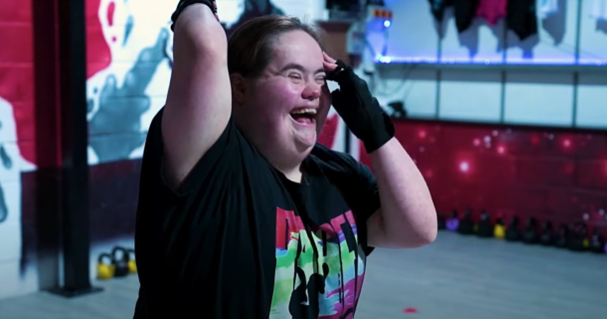 Hijinx actor, Bethany Freeman, stands with her arms up as she laughs while standing in a dance studio.