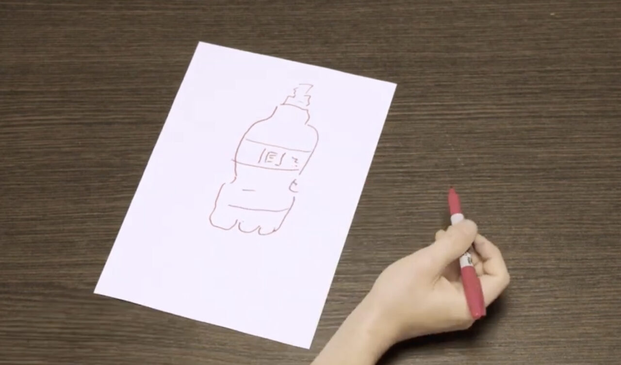 A hand holds a red marker next to a drawing of a bottle on a white piece of paper.
