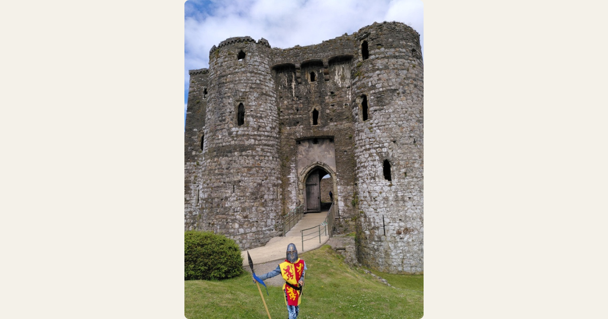 A person dressed in historical clothing standing outside a castle.