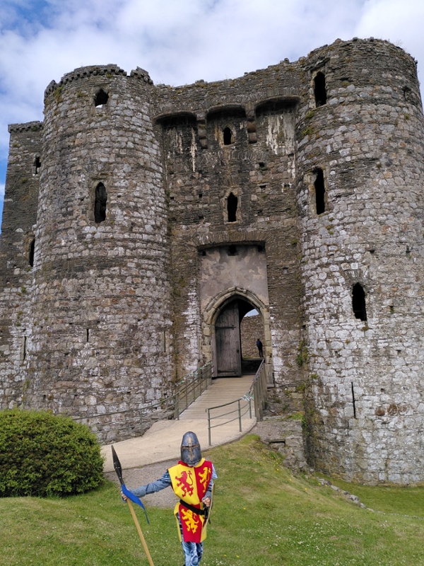 A person dressed in historical clothing standing outside a castle.