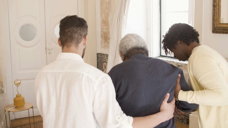 Image of elderly man being helped by carers